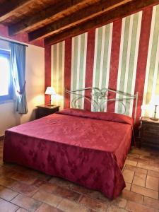 a bedroom with a red bed with a striped wall at Villa Redona in Entratico