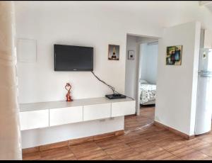 a living room with a tv on a white wall at Chale Cantinho do Sol Catarina Home Club in Mairinque +21 photos