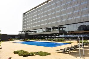 a building with a swimming pool and chairs and umbrellas at Ceiba Hotel Bissau in Bissau