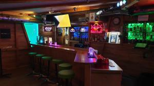 a bar with green stools and a counter with neon lights at Hotel Mira in Sedrun