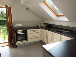 uma cozinha com armários brancos, um lavatório e uma janela em Kneese Loft em Chesterfield