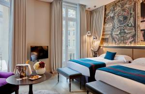 una habitación de hotel con dos camas y una mesa en Hotel Indigo Paris - Opera by IHG, en París 139 fotos más