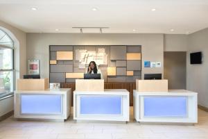 a woman sitting in a waiting room with a laptop at Holiday Inn Express & Suites S Lake Buena Vista by IHG in Kissimmee