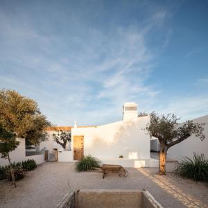 a white house with a bench in the courtyard at Hospedaria in Alvisquer