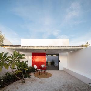 a house with a red wall and a table and chairs at Hospedaria in Alvisquer