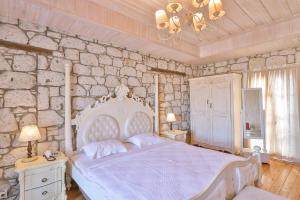 a bedroom with a white bed and a stone wall at Imren Han Hotel - Special Category in Alaçatı