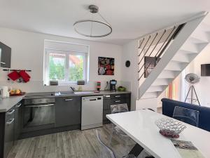una cocina con electrodomésticos de acero inoxidable y una escalera en * Maison aux portes de Troyes en Champagne * en Sainte-Maure