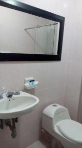 a bathroom with a sink and a toilet and a mirror at Hotel Yuldama Rodadero Inn in Santa Marta