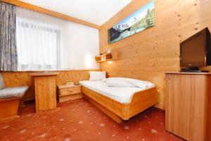 a small bedroom with a bed and a tv at Hotel Silvretta in Sankt Gallenkirch
