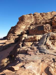 una montaña rocosa con escalones que conducen a un edificio en Obeid's Bedouin Life Camp, en Wadi Rum