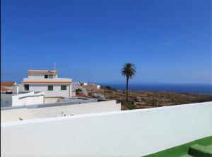 un edificio blanco con una palmera y el océano en Apartament in arico, en Arico el Nuevo