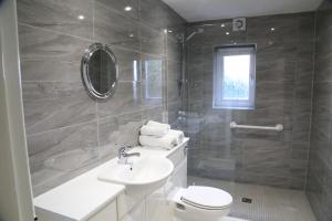 a bathroom with a sink and a toilet and a shower at La Suisse Serviced Apartments in Manchester