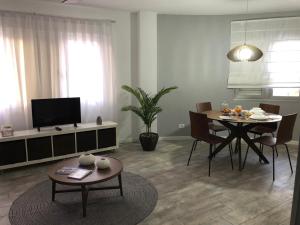 ein Wohnzimmer mit einem Esstisch und einem TV in der Unterkunft Apartamento AQUAVIVA - El Médano in El Médano