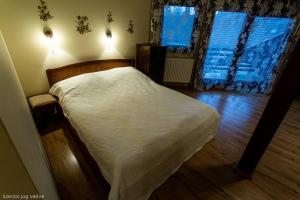 Schlafzimmer mit einem Bett mit weißer Bettwäsche und einem Fenster in der Unterkunft Balázs Szálló in Gyula