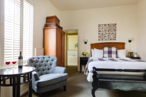 a hotel room with a bed, chair, desk and a lamp at Maison Fleurie, A Four Sisters Inn in Yountville