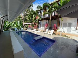 a swimming pool with chairs and a house at Hotel Ballena Dorada in Uvita