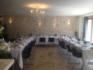 a long table with white tables and chairs in a room at La Ferme des Moulineaux in Bailly