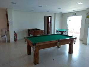einen Billardtisch in einem Zimmer mit 2 Stühlen in der Unterkunft Apto. De frente pro Mar in Praia Grande