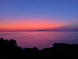 a sunset over the ocean with a mountain in the distance at B&B La Danza del Mare in Anacapri