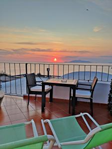 a table and chairs on a balcony with the sunset at B&B La Danza del Mare in Anacapri