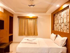 a bedroom with a white bed and a window at Hotel Grand Suites in Bangalore