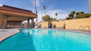 a large blue swimming pool next to a brick wall at Best Western Pasadena Inn in Pasadena