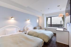 two beds in a hotel room with a window at Kobe Sannomiya Union Hotel in Kobe