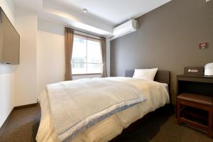 1 dormitorio con cama blanca y ventana en G-SQUARE, en Yamagata