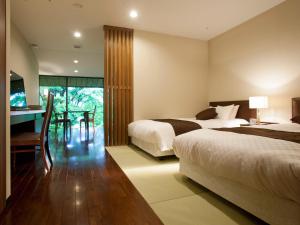 een slaapkamer met 2 bedden, een bureau en een tafel bij Nagaragawa Seiryu Hotel in Gifu