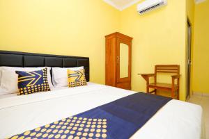 een slaapkamer met een bed en een stoel erin bij SPOT ON 2821 Griya Kawula Syariah in Solo