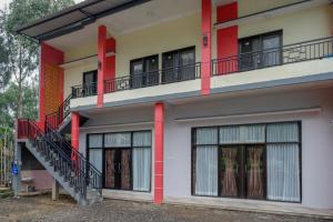 a building with red columns and windows and a staircase at RedDoorz @ Gerbang Dieng Plateau Area in Wonosobo