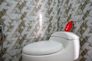 a bathroom with a white toilet with a red seat at RedDoorz @ Gerbang Dieng Plateau Area in Wonosobo