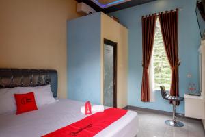 una camera da letto con un letto con una coperta rossa e una finestra di RedDoorz @ Gerbang Dieng Plateau Area a Wonosobo