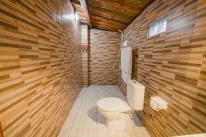 a bathroom with a toilet and a wooden wall at Hotra Hill Cottage in Nusa Penida