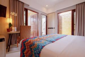 Aruna Senggigi Resort & Convention في سينغيغي: غرفة نوم بسرير ومكتب ونوافذ