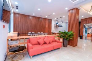 a red couch in a lobby with a table at MOMIZI Hotel HAI PHONG in Hai Phong