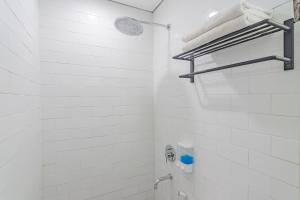 uma casa de banho branca com um chuveiro e um lavatório. em RedDoorz Premium @ Hotel Hebat em Bandung