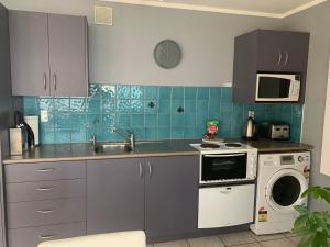 a kitchen with a sink and a stove and a microwave at Beach Lane Apartment in Whangarei +30 photos