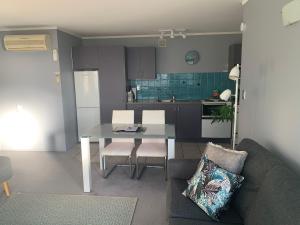 a living room with a table and a kitchen at Beach Lane Apartment in Whangarei