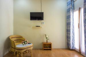 a room with a chair and a tv on the wall at OYO 1696 Sapo Rumbia in Berastagi