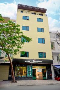 a tall yellow building with a sign on it at MOMIZI Hotel HAI PHONG in Hai Phong