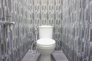 a bathroom with a white toilet in a tiled wall at OYO 1696 Sapo Rumbia in Berastagi