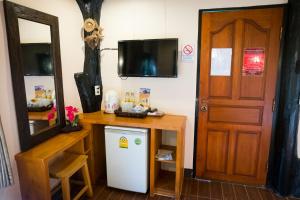 Cette chambre comprend un réfrigérateur, une table et une porte. dans l'établissement Lee Wine Ruk Thai Resort, à Ban Rak Thai