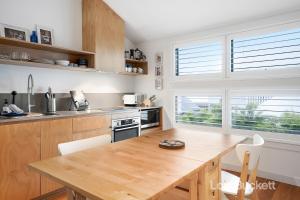 a kitchen with a wooden table and a kitchen withwindows at The Lennoxhaus in Lennox Head +14 photos