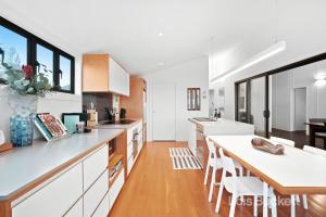 a kitchen with white cabinets and a wooden table at The Lennoxhaus in Lennox Head