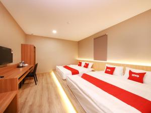two beds in a hotel room with a desk and a tv at Hotel 101 Ulu Tiram in Ulu Tiram