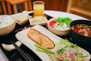 une table avec une assiette de nourriture et des bols de soupe dans l'établissement MOMIZI Hotel HAI PHONG, à Hai Phong