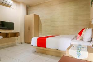 a hotel room with a bed and a television at OYO 2581 Ketut Smile in Denpasar