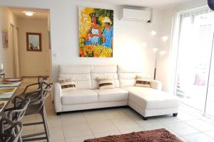 a white couch in a living room with a painting at City'appart in Papeete