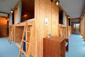 - une rangée de lits superposés dans un dortoir doté d'un mur en bois dans l'établissement COCORETO The Guesthouse Daikon Island, à Matsue